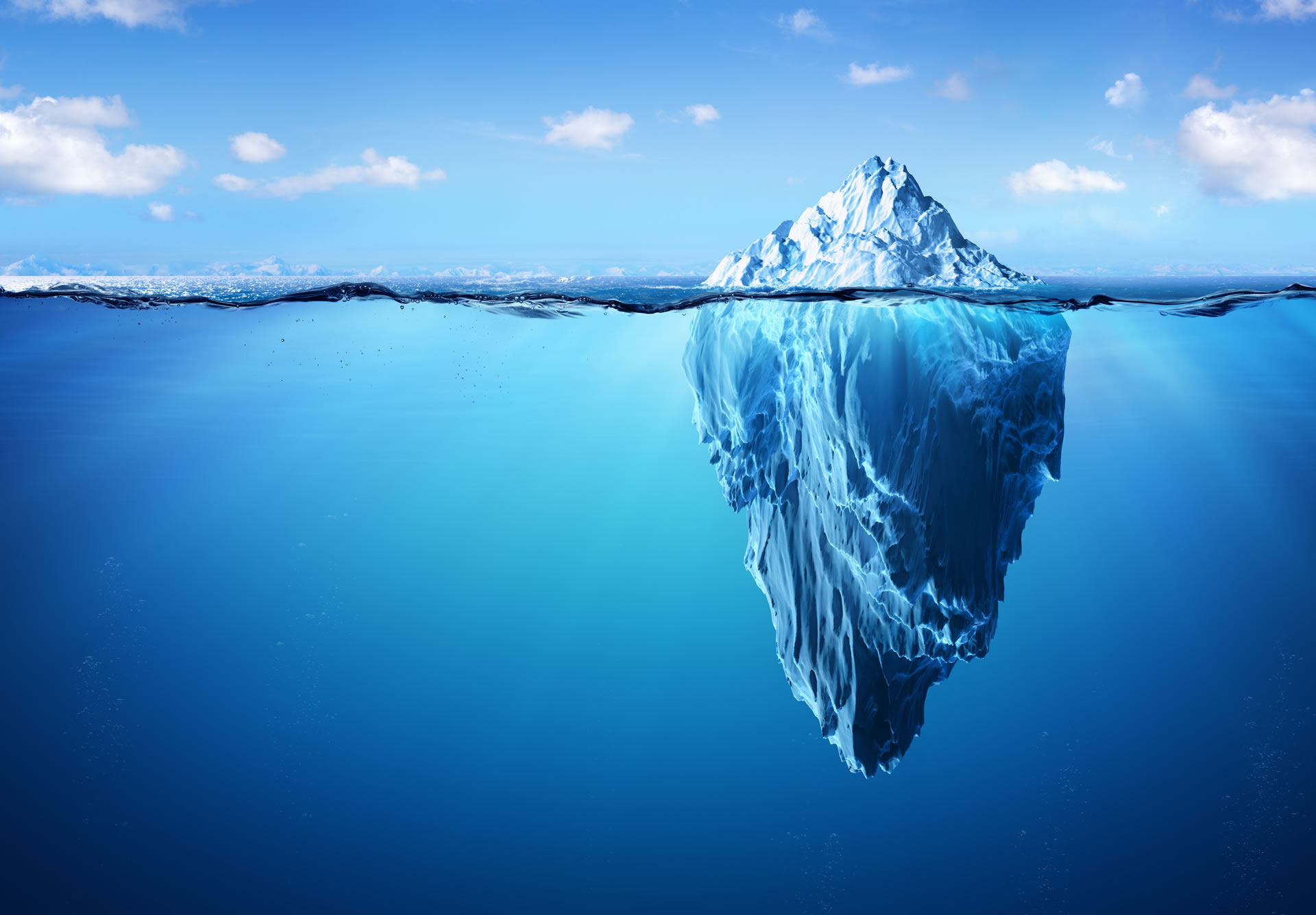 Ein Eisblock der im Wasser ist und darüber ist ein blauer Himmel mit ein paar weißen Wolken